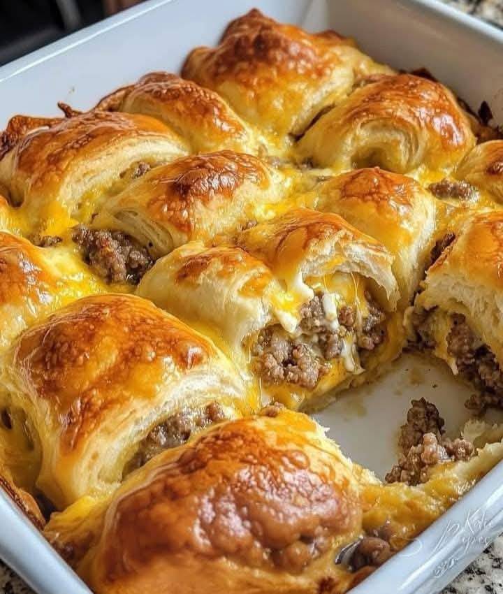 Instrukcje krok po kroku: 1. Rozgrzej piekarnik: Rozgrzej piekarnik do 375°F (190°C). Wyłóż blachę do pieczenia papierem pergaminowym, aby zapobiec przywieraniu.  2. Przygotuj kiełbaski: Jeśli używasz surowej kiełbasy, smaż kiełbaski na patelni na średnim ogniu, aż będą w pełni ugotowane. Przed obróbką pozwól im lekko ostygnąć.  3. Rozwałkuj ciasto: Otwórz puszkę z ciastem półksiężycowym i podziel je na trójkąty wzdłuż perforacji. Połóż trójkąty płasko na blasze wyłożonej papierem do pieczenia.  4. Dodaj nadzienie:  Umieść kiełbaskę na szerokim końcu każdego półksiężyca. Jeśli chcesz, posyp kiełbaskę odrobiną startego sera cheddar przed zwinięciem. 5. Zwiń półksiężyce: Zaczynając od szerokiego końca, zwiń każdy trójkąt, otaczając kiełbaskę w środku. Umieść bułki szwem do dołu na blasze do pieczenia, aby zapobiec ich rozplataniu się podczas pieczenia.  6. Posmaruj i udekoruj: Używając pędzelka do ciasta, lekko posmaruj wierzch rogalików roztrzepanym jajkiem. Jeśli chcesz, posyp sezamem lub makiem, aby uzyskać dodatkową teksturę i smak.  7. Pieczenie: Piecz w nagrzanym piekarniku przez 12–15 minut, lub do momentu, aż rogaliki będą złocistobrązowe i rozpadną się na kawałki.  8. Ostudź i podaj: Wyjmij bułki z piekarnika i pozwól im ostygnąć przez kilka minut przed podaniem. Najlepiej smakują na ciepło!  Wskazówki dotyczące sukcesu: Wstępnie ugotowana kiełbasa: Oszczędź czas, używając w pełni ugotowanych kiełbasek. Jeśli używasz surowej kiełbasy, upewnij się, że jest dokładnie ugotowana, zanim obtoczysz ją w cieście.  Opcje sera: Zamień cheddar na inne sery, np. pepper jack lub mozzarellę, aby nadać potrawie nowego smaku.  Sos do maczania: Podawaj te rogaliki z ketchupem, musztardą lub śmietankowym sosem do maczania, aby nadać im dodatkowego smaku.  Przygotuj z wyprzedzeniem: Możesz przygotować te bułki poprzedniego wieczoru i schłodzić je. Upiecz świeże rano, aby uzyskać gorące, łuszczące się śniadanie.