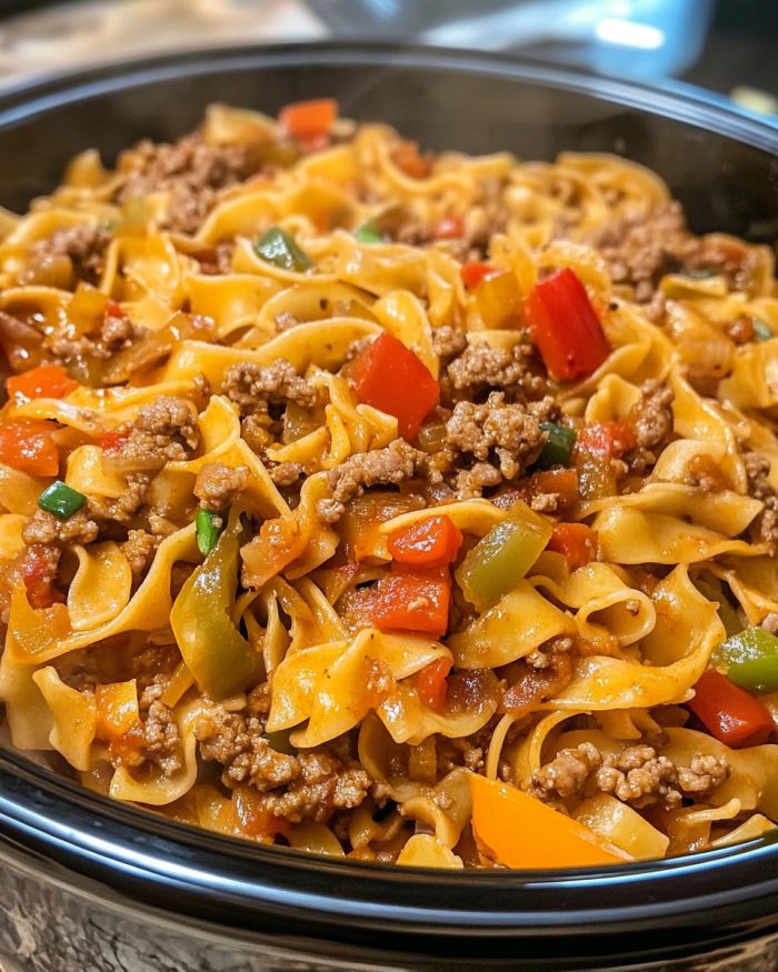 Slow Cooker Italian Drunken Noodle to zachęcające danie fusion, które łączy włoskie i amerykańskie smaki w sposób, który jest zarówno pocieszający, jak i egzotyczny. Pochodzący z tętniących życiem kuchni Włoch, nazwa „drunken noodle” wskazuje na odrobinę bogatego czerwonego wina, które podnosi profil smakowy tego dania. Jest idealne dla zapracowanych osób, które chcą cieszyć się zdrowym, ale wyrafinowanym posiłkiem bez zamieszania. Korzystanie z wolnowaru sprawia, że ​​proces jest bezproblemowy, pozwalając smakom pięknie połączyć się z czasem. To sycące danie doskonale komponuje się z prostą sałatką polaną lekkim winegretem, równoważąc bogate smaki makaronu. Możesz je również zjeść z kromką chrupiącego włoskiego chleba, idealnego do wchłonięcia resztek sosu. Jeśli chcesz, aby stało się to kompletnym daniem, rozważ podanie go z pieczonymi warzywami lub kremowym risotto. Reklama Makaron włoski pijany w wolnowarze Porcje: 6-8  Składniki 1 funt włoskiej kiełbasy, bez osłonek 1 duża cebula, pokrojona w plasterki 4 ząbki czosnku, drobno posiekane 1 papryka, pokrojona w plasterki 1 puszka (14,5 uncji) pokrojonych w kostkę pomidorów, nieodsączonych 1/2 szklanki wytrawnego czerwonego wina 1 szklanka bulionu z kurczaka 1 łyżka koncentratu pomidorowego 1 łyżeczka suszonej bazylii 1 łyżeczka suszonego oregano 1/2 łyżeczki płatków czerwonej papryki Sól i pieprz do smaku 8 uncji szerokich makaronu jajecznego 1/2 szklanki startego parmezanu Świeża bazylia do dekoracji Wskazówki 1. Na patelni, na średnim ogniu, podsmaż włoską kiełbasę, rozdrabniając ją na małe kawałki w trakcie smażenia. 2. Przełóż ugotowaną kiełbasę do wolnowaru, dodaj pokrojoną cebulę, czosnek i paprykę. 3. Dodaj pokrojone w kostkę pomidory wraz z sokiem, czerwone wino, bulion z kurczaka i koncentrat pomidorowy. 4. Posyp suszoną bazylią, oregano, płatkami czerwonej papryki, dopraw solą i pieprzem. 5. Wymieszaj wszystko, następnie przykryj i gotuj na małym ogniu przez 6–8 godzin. 6. Około 20-30 minut przed podaniem ugotuj makaron jajeczny zgodnie z instrukcją na opakowaniu, aż będzie al dente. Odcedź i wmieszaj do wolnowaru. 7. Dopraw do smaku, jeśli to konieczne, a następnie posyp wierzch startym parmezanem. 8. Przed podaniem udekoruj świeżą bazylią.   Reklama Wariacje i wskazówki Aby uzyskać lżejszą wersję, spróbuj użyć kiełbasy z indyka zamiast wieprzowiny. Jeśli wolisz opcję wegetariańską, możesz zastąpić kiełbasę roślinnym mięsem lub większą ilością warzyw, takich jak cukinia i pieczarki. Ponadto eksperymentowanie z różnymi rodzajami makaronu, takimi jak pappardelle lub nawet makaron bezglutenowy, może dostosować danie do Twoich potrzeb dietetycznych. Możesz dodać odrobinę śmietanki kremówki, aby uzyskać bogatszy sos.